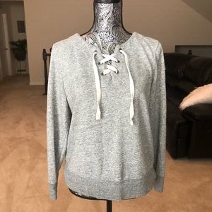A gray sweat shirt with crosses strings.